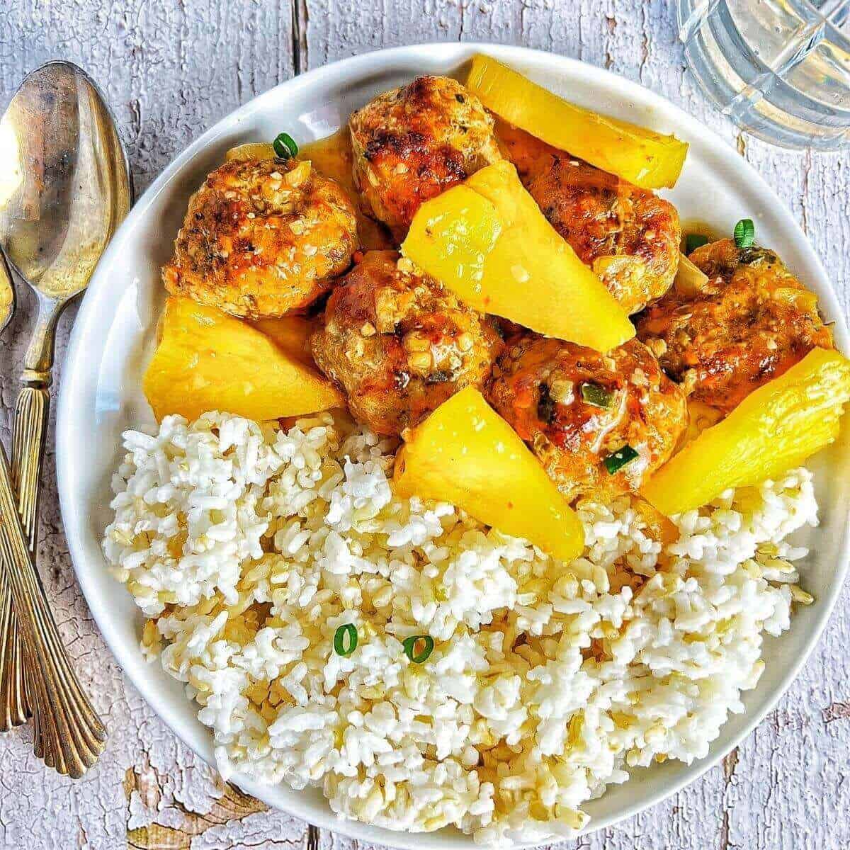 a plate of sweet and sour sauce meatballs with pineapple