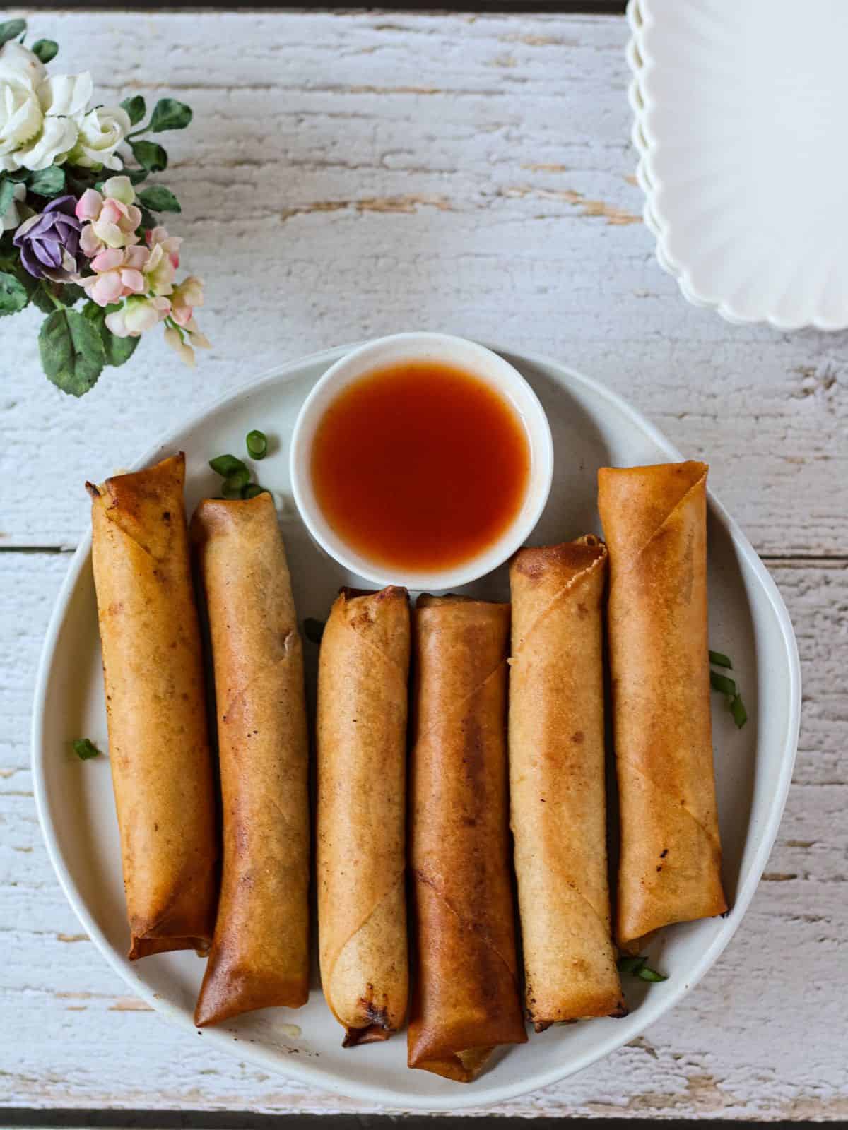 Pork lumpia in a table with dipping sauce.