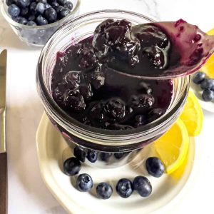 Blueberry jam in jar and spoon.
