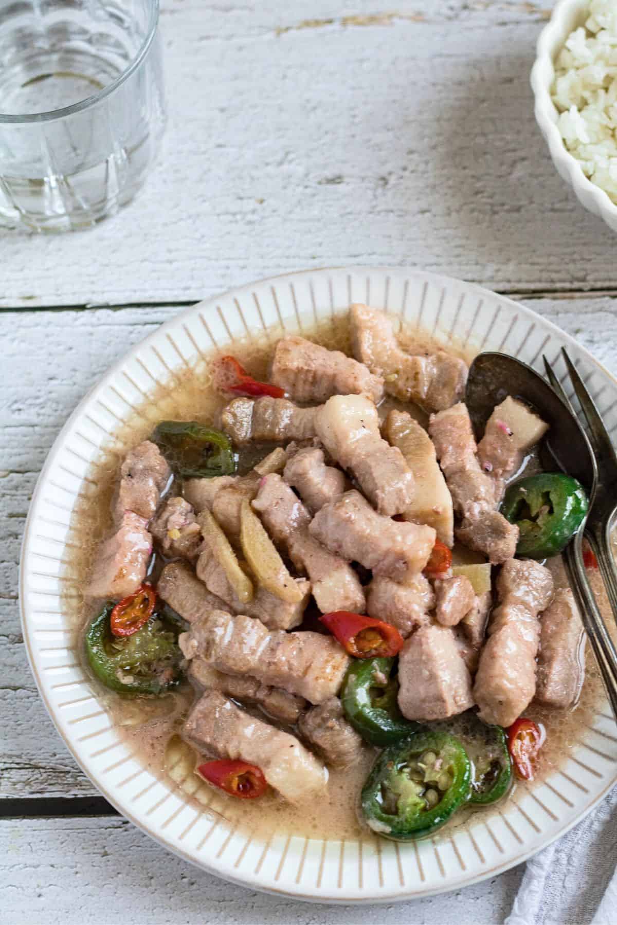 Finish dish of bicol express in a plate with spoon and fork.