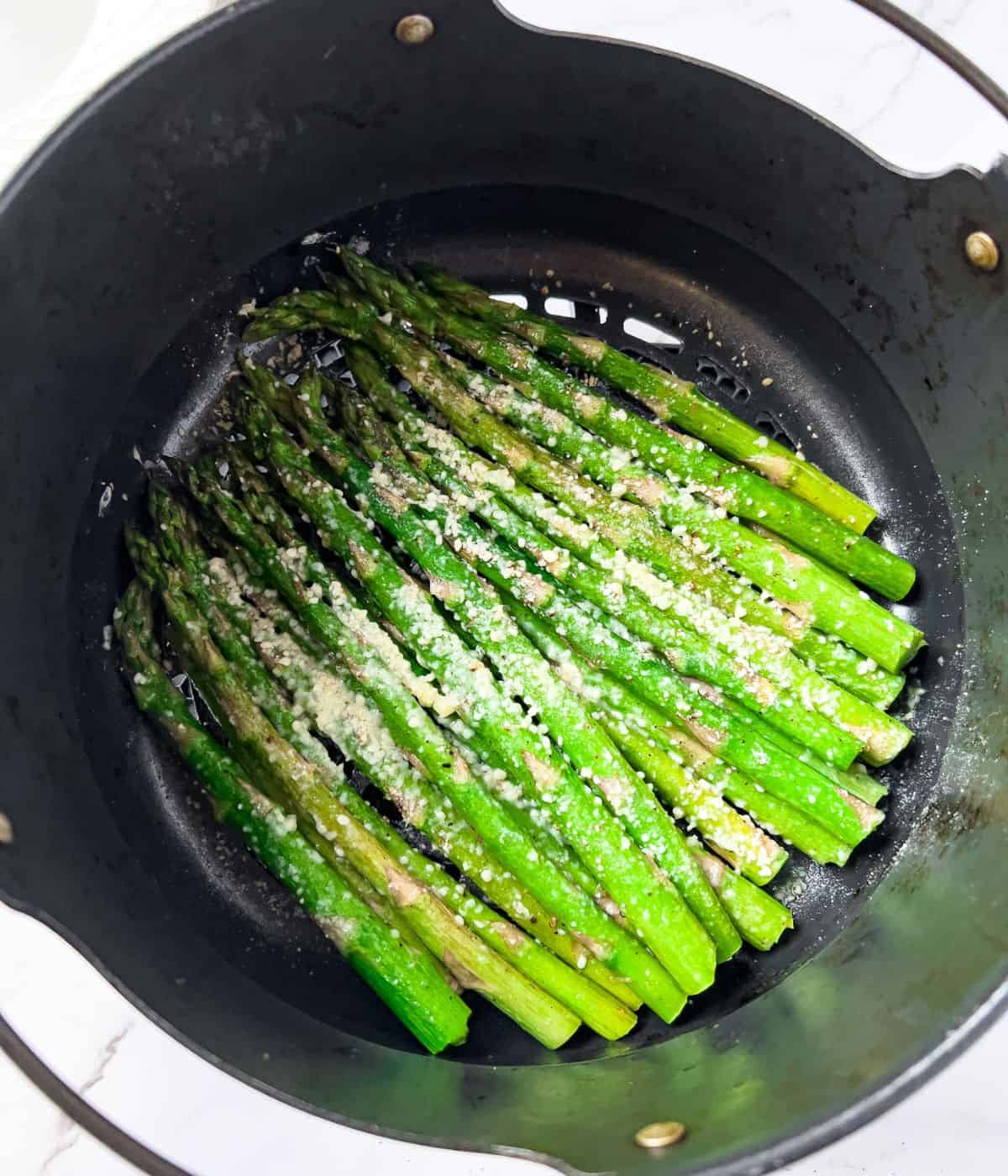 Cooked asparagus in an air-fryer basket.