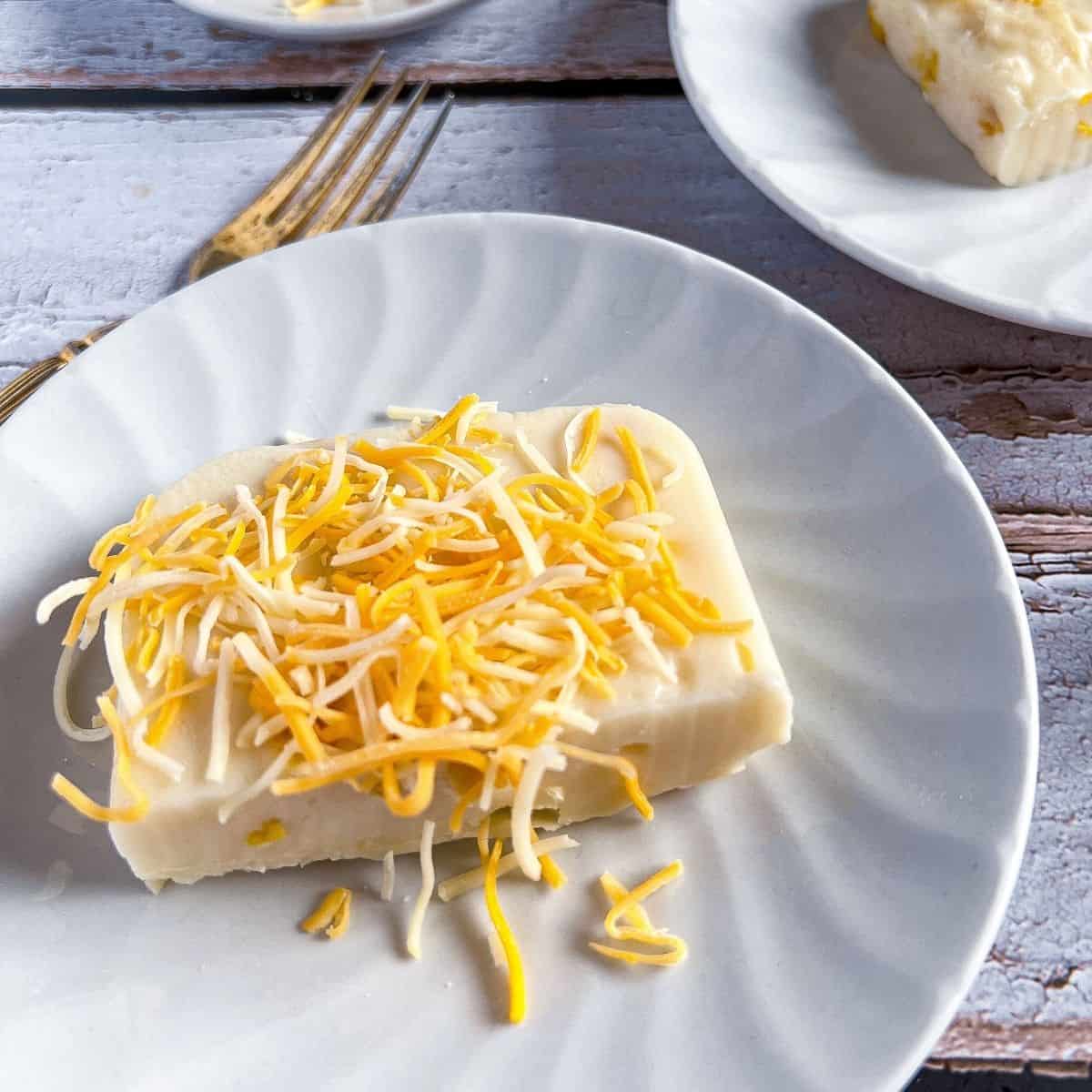 A plate of maja blanca with cheese on top.
