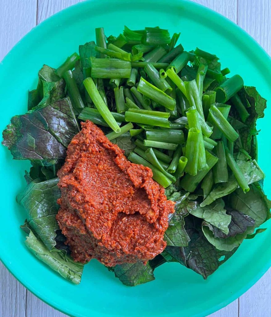 Combining red chili paste and mustard greens.