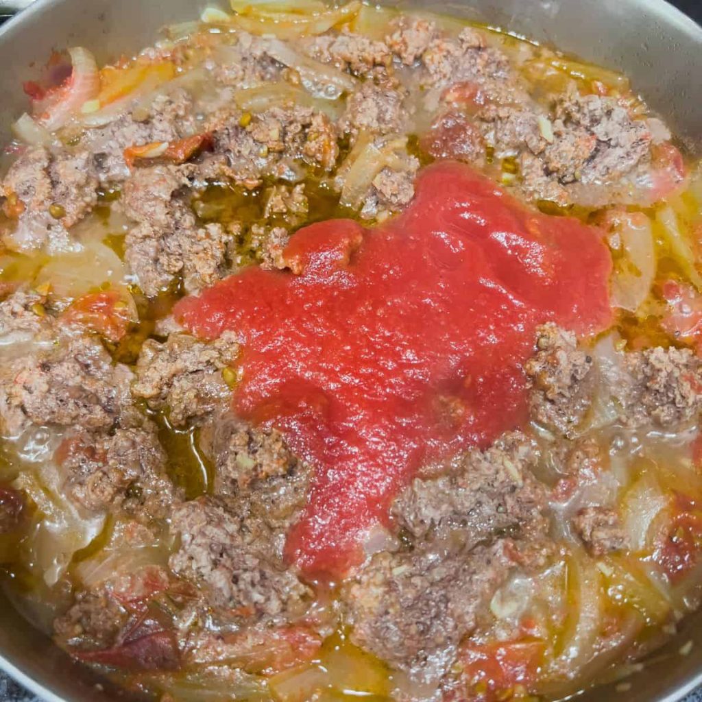 Adding tomato sauce to the dish.