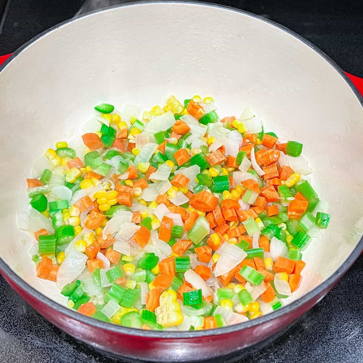 Cooking carrots, celery, and corn in a dutch oven.