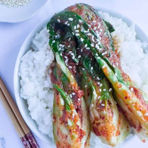 A bowl of rice with bok choy kimchi on top.