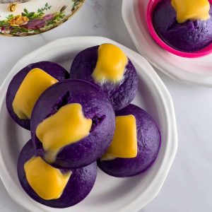 Ube puto with cheese serve on plate with a cup of tea.
