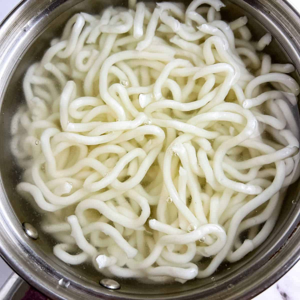 Cooking udon noodles in boiling water.