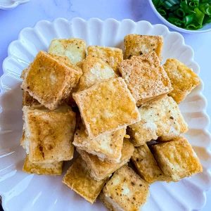 Crispy fried tofu on a white plate.