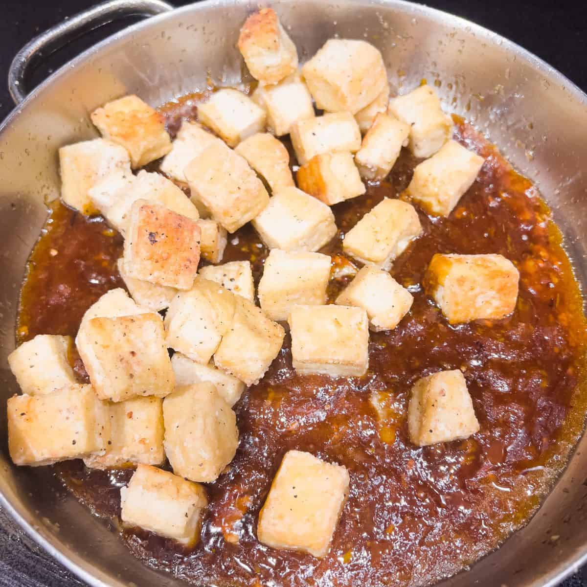 Combining orange tofu sauce with the fried tofu.