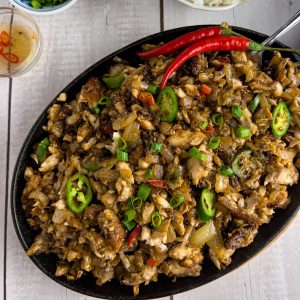 Finish dish of bangus sisig in a sizzling platter with red chili, chopped green onions and rice.