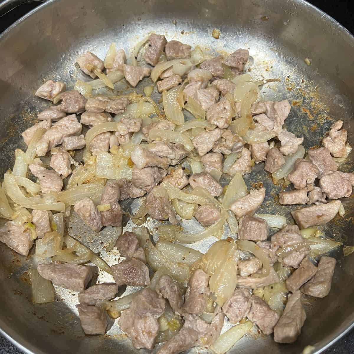 Cooking onion, garlic, and meat in a skillet.