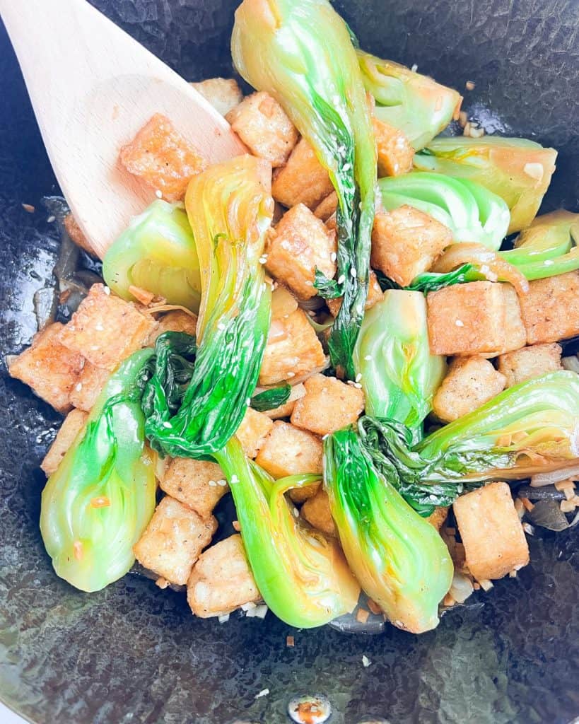 Bok choy and tofu stir-fry in a wok.