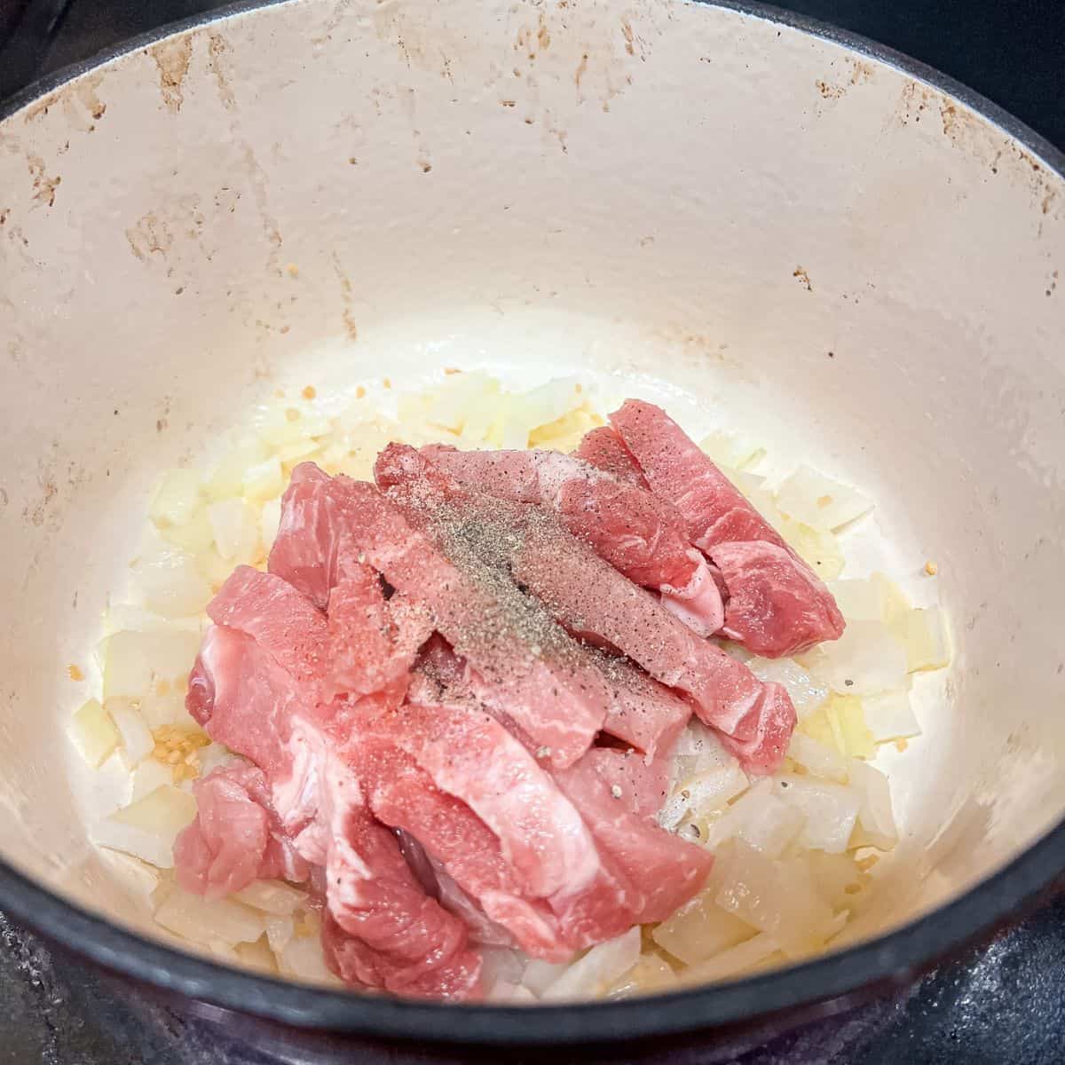 Cooking onion, garlic and pork in a dutch oven.