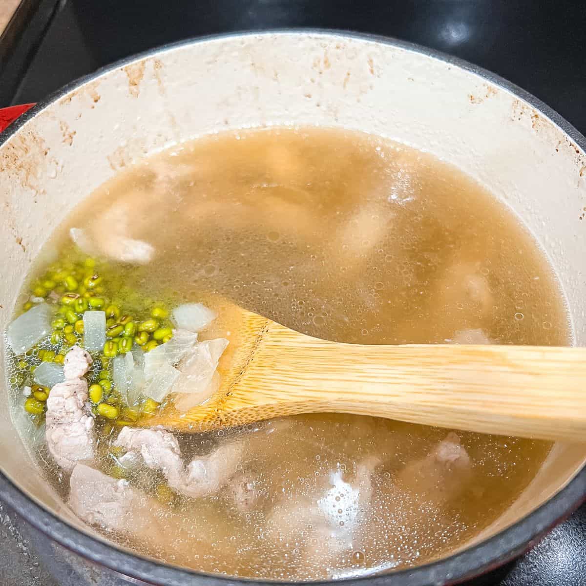Adding mung beans and beef broth to the pot.