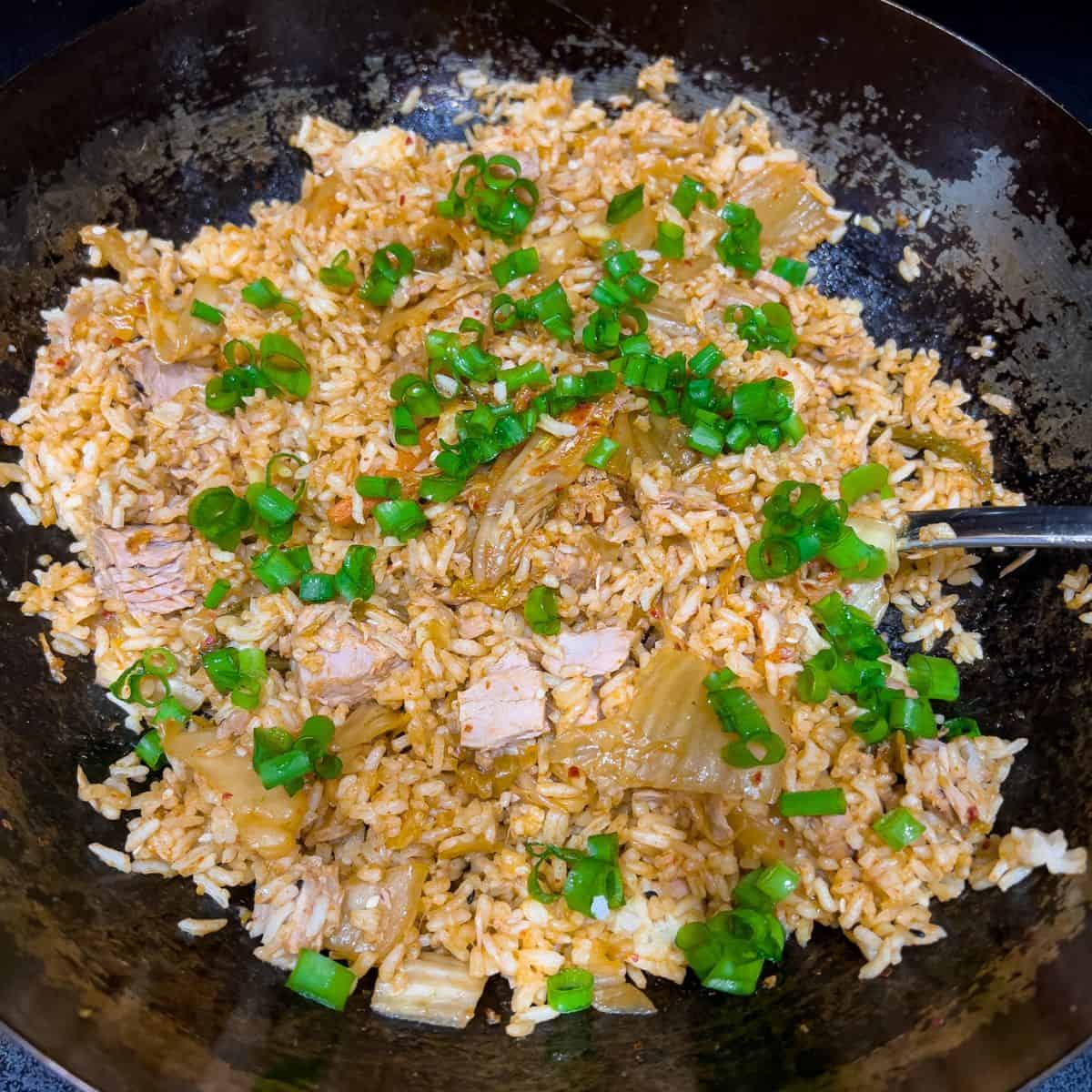 Adding green onions to the fried rice.