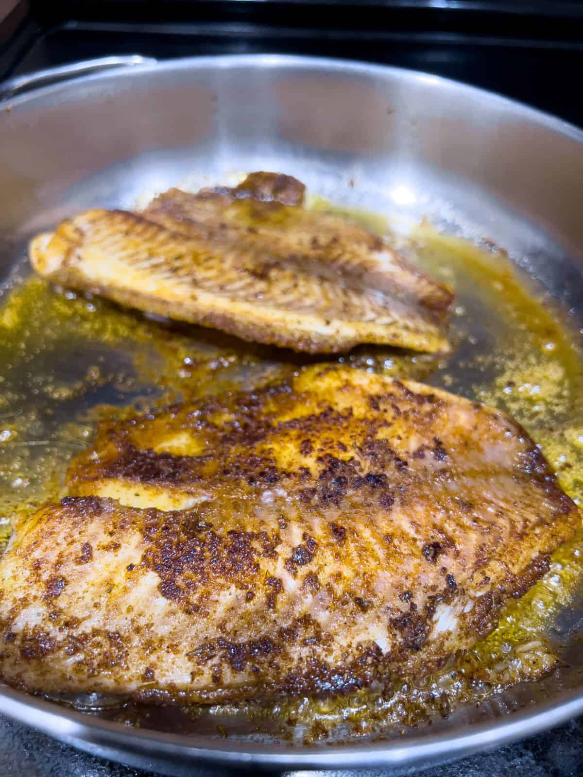 Frying the blackened tilapia fish fillet.