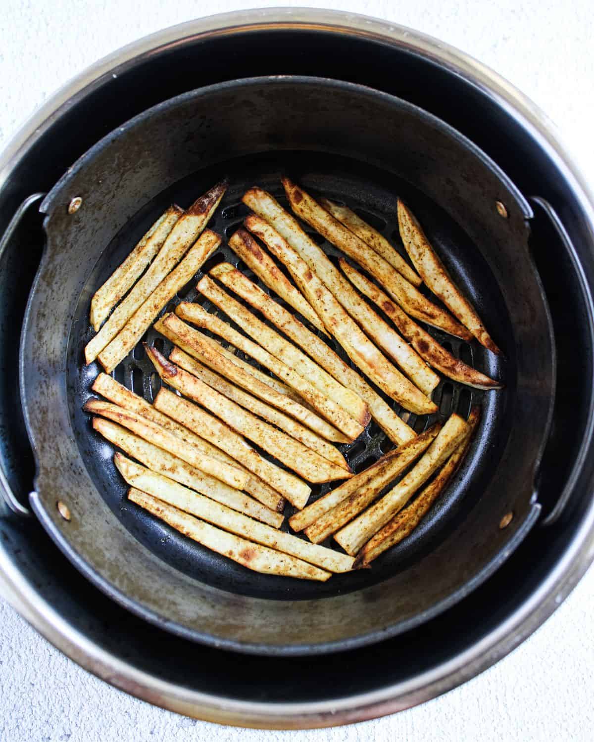 Cooked sweet potato fries in the air-fryer basket.