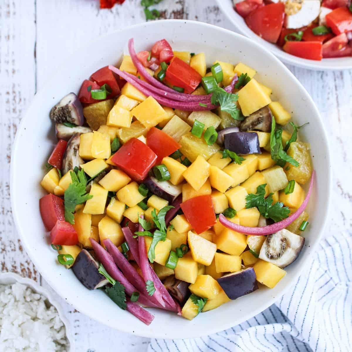 Mango pineapple tomato salad in a bowl, ready to eat.