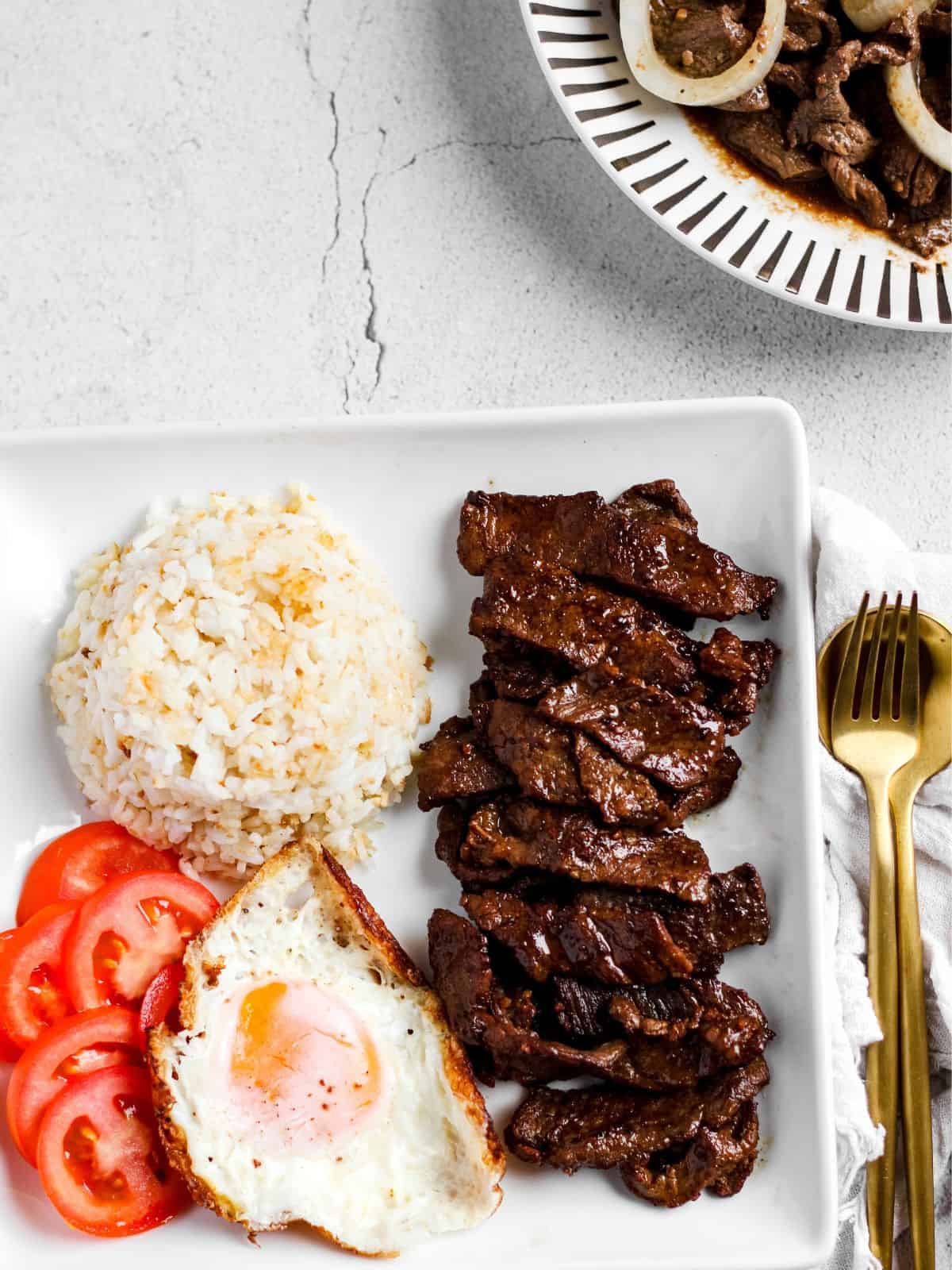 Filipino beef tapa in the table and ready to eat with fried rice and fried egg.