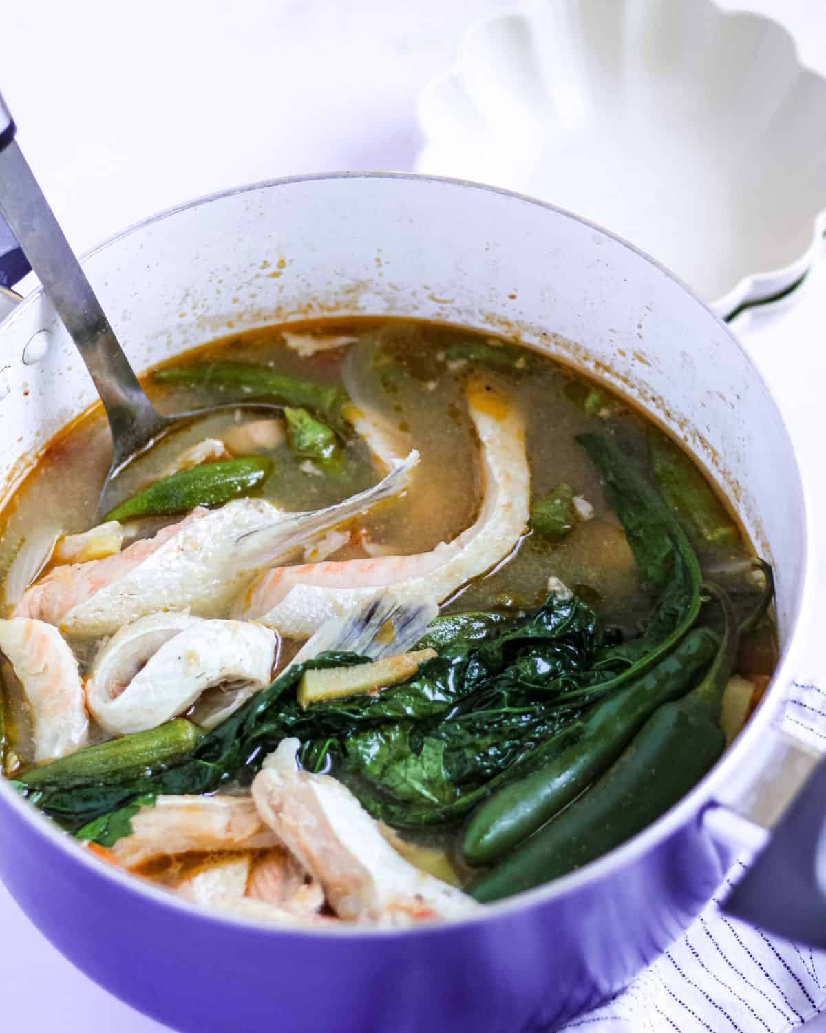 Cooked salmon belly sinigang in a blue pot.