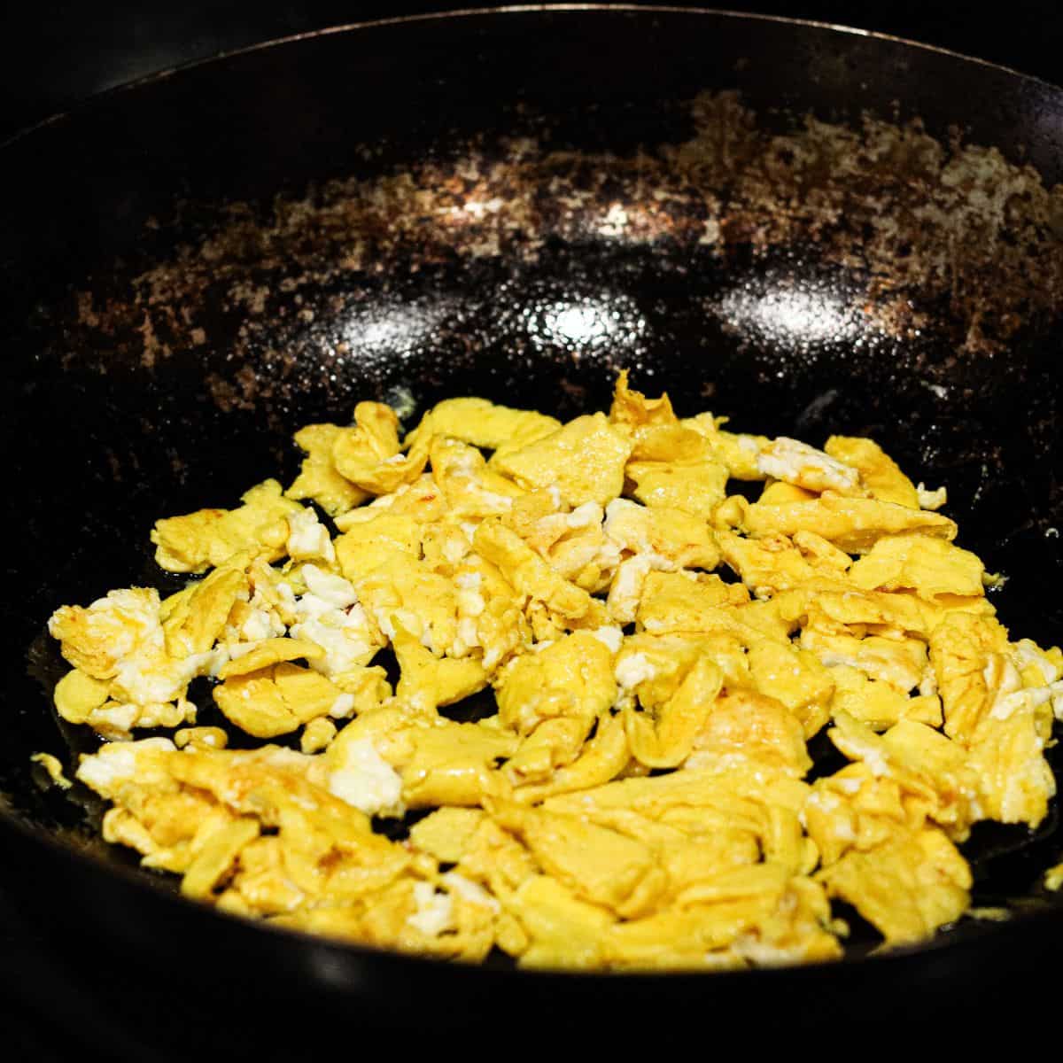 Scramble the egg in a wok.