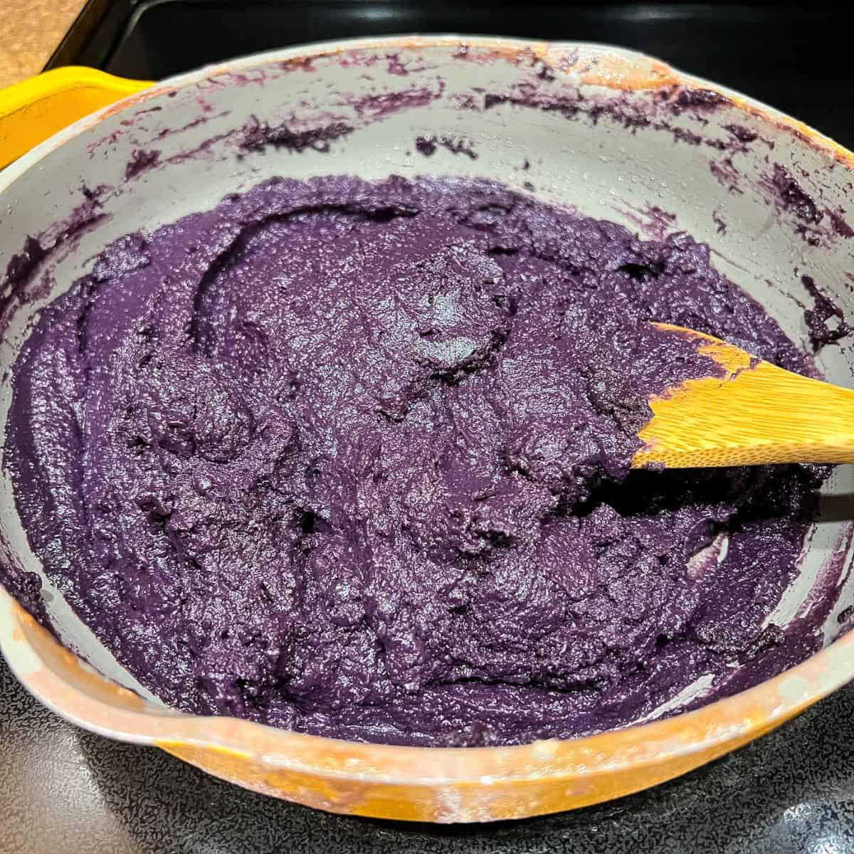 Stirring and cooking the ube halaya in a skillet.