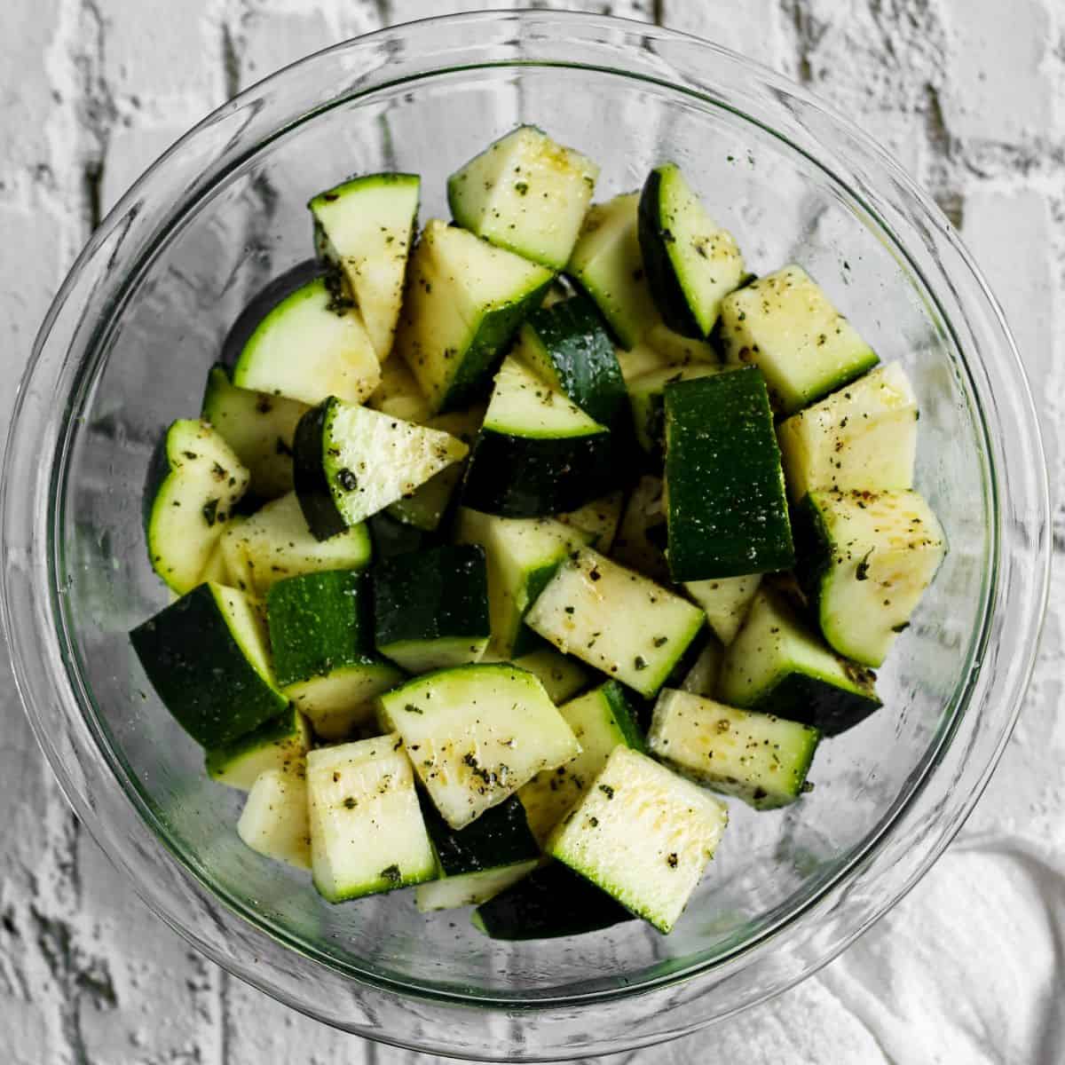 A bowl with zucchini and olive oil seasonings.