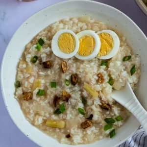 Finish dish of arroz caldo with toppings such as boiled eggs and toasted garlic.