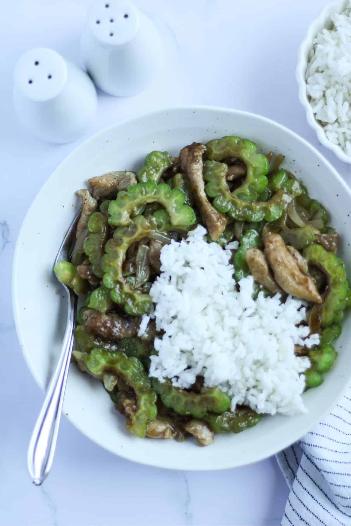 Chicken bitter melon stir-fry with oyster sauce dish on a plate with rice.