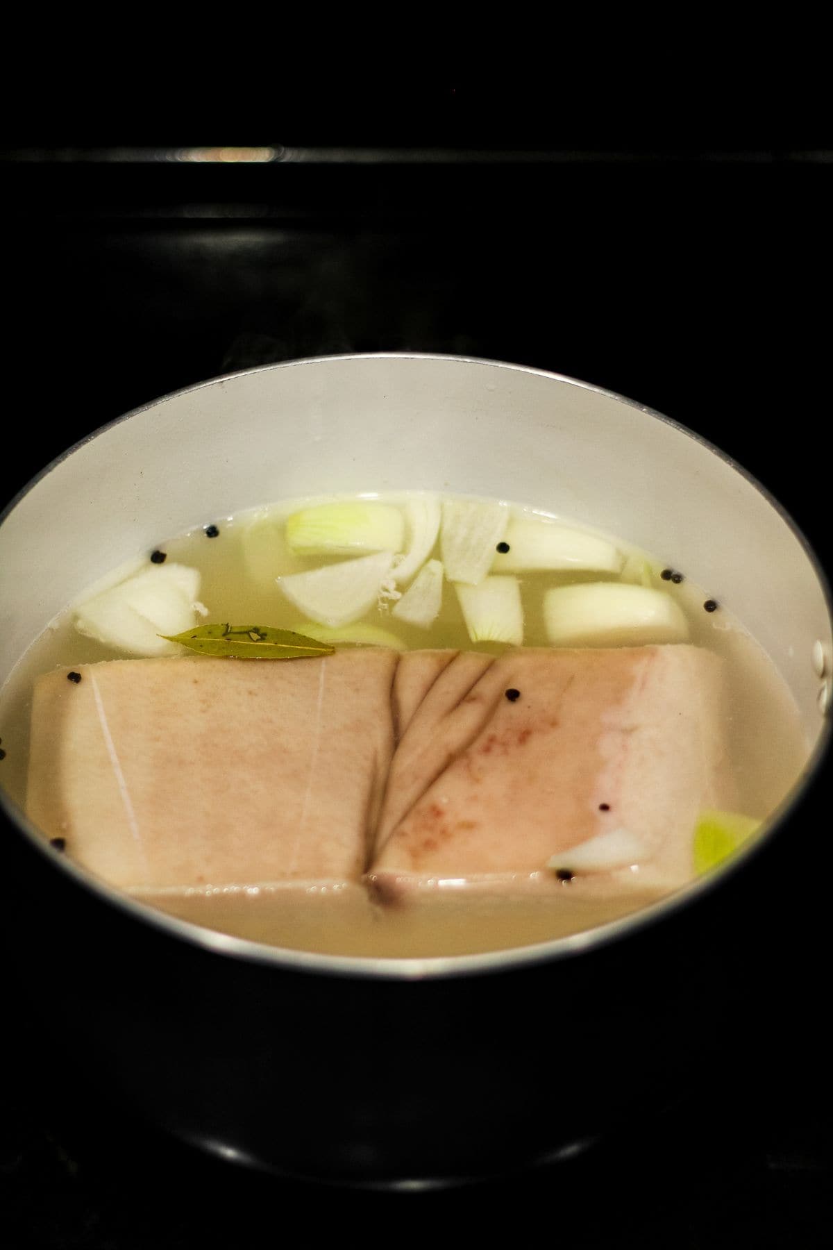 Pork belly in a pot with seasoning and spices.