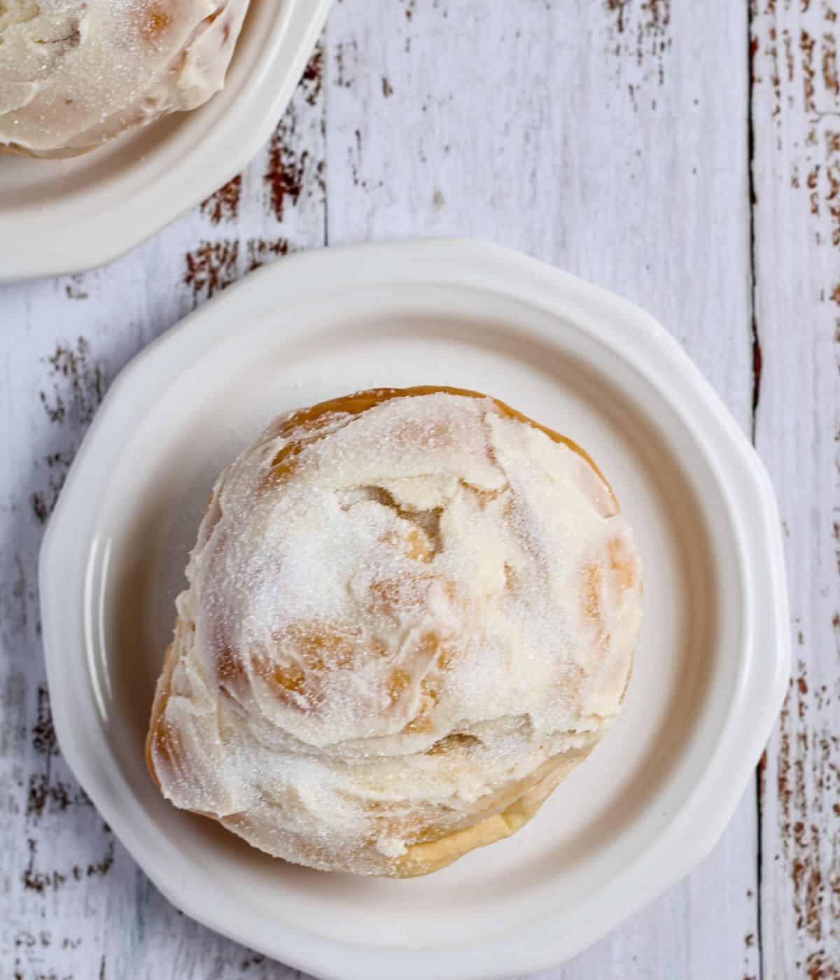 Baked ensaymada on a plate with butter and sugar.