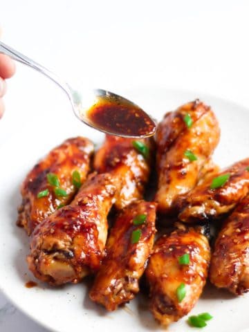 Finish dish of honey garlic chicken wings with a spoonful sauce.