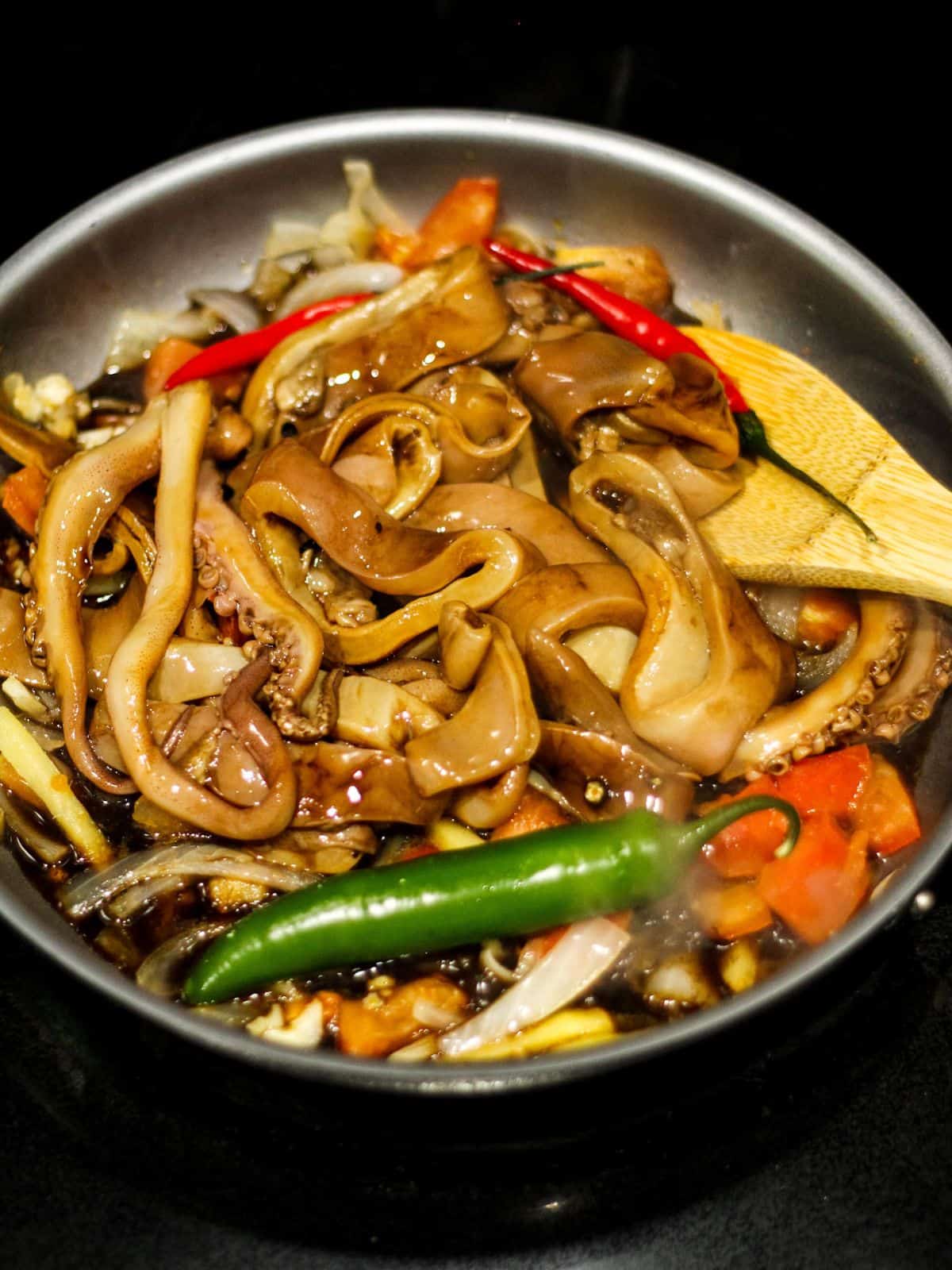 Adding marinated squid in the skillet.