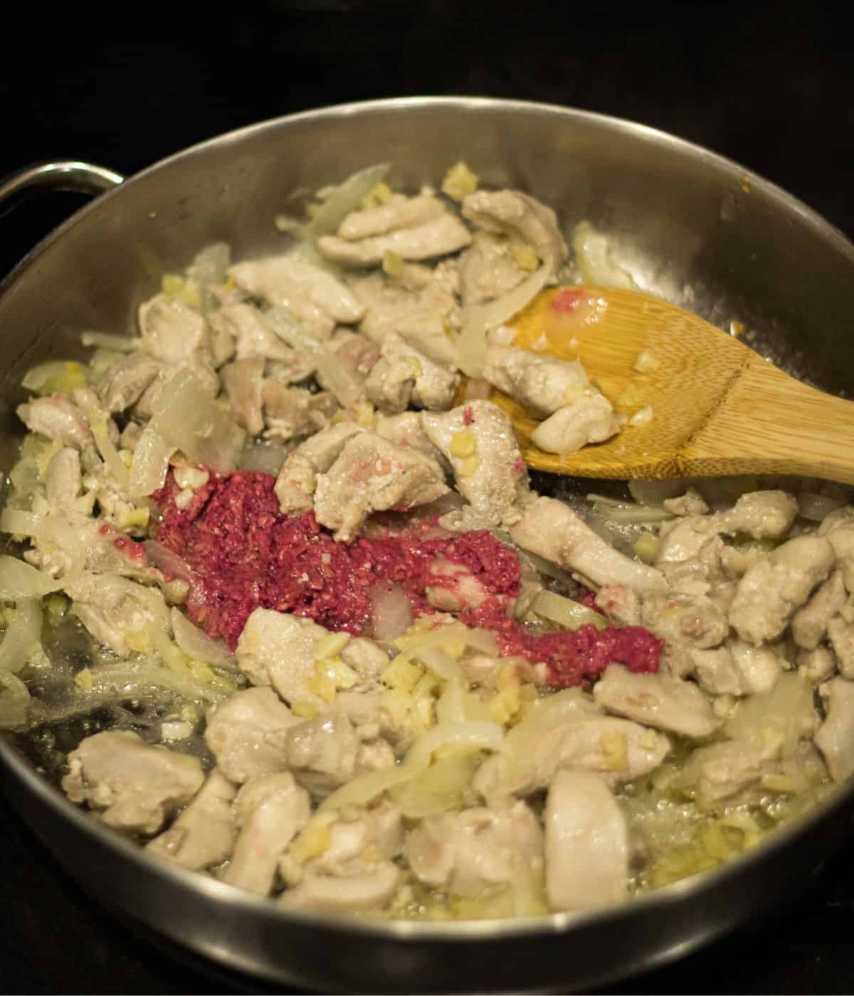 Sauted chicken and shrimp paste in a skillet.