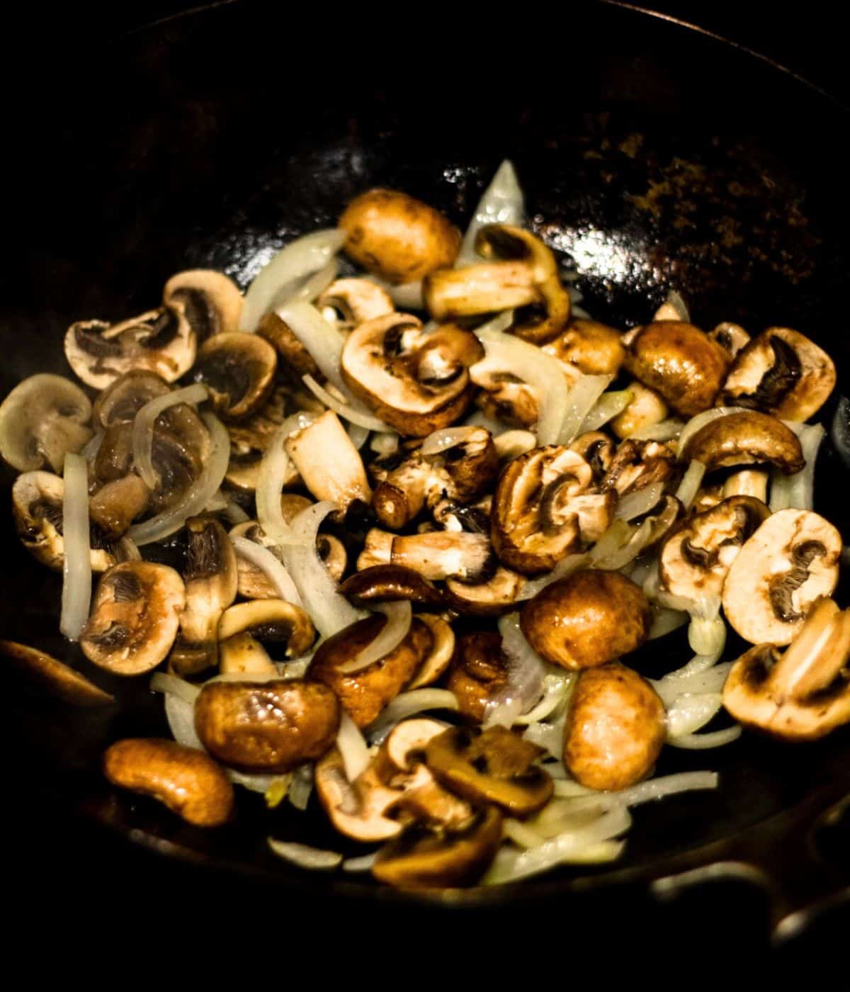 Cooking onion and mushrooms in a wok.