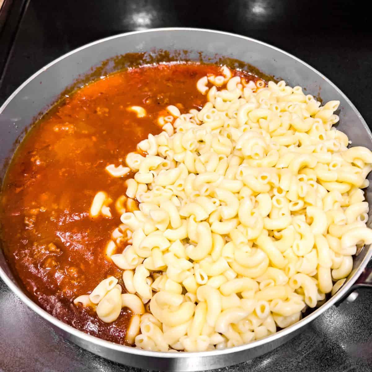Combining cooked macaroni and the sauce.